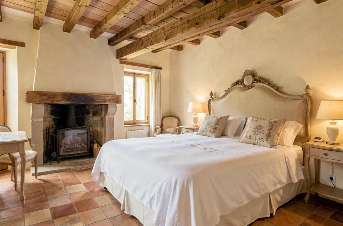 Chambre de charme avec poutres apparentes et cheminée en pierre au Bois des Chambres