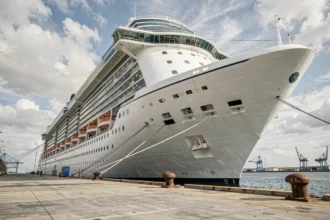 Vue grand angle du plus grand bateau de croisière amarré au terminal portuaire, avec sa coque blanche imposante et ses multiples ponts de balcons